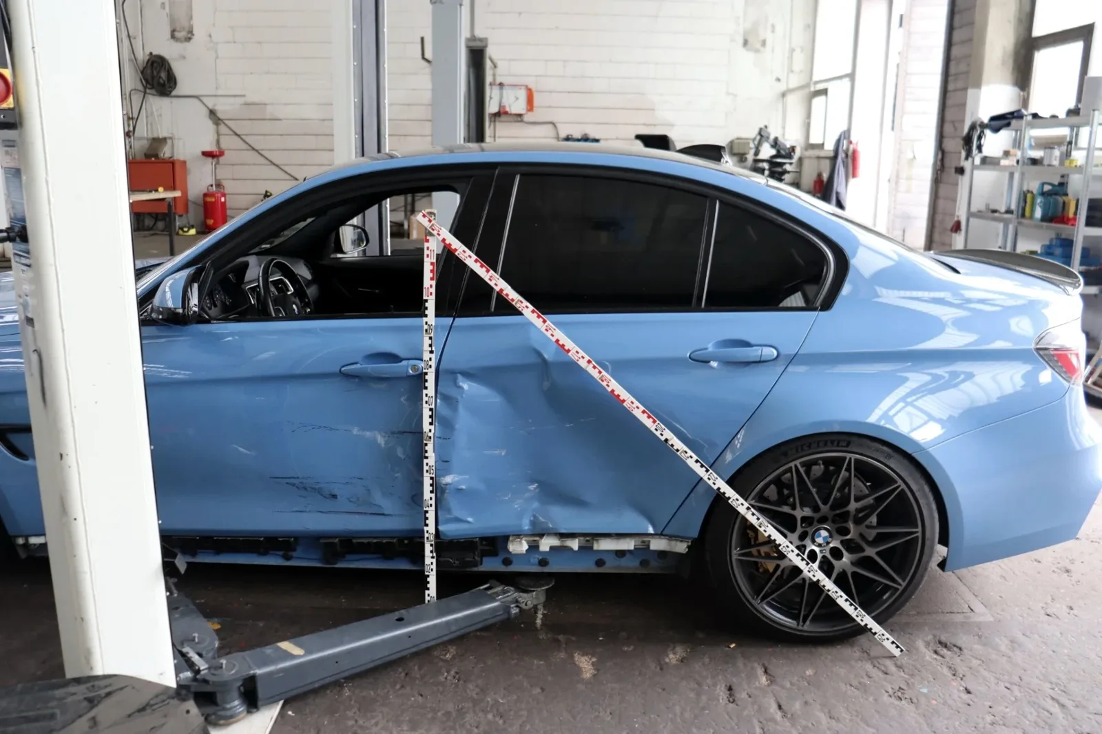 Blauer BMW mit Seitenschaden, Schadenaufnahme mit Messlatte